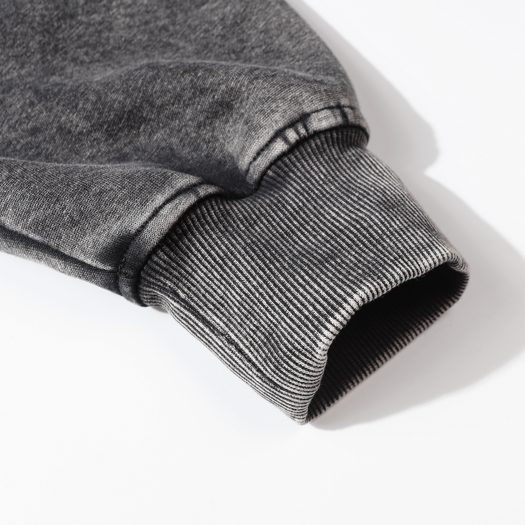Close-up of dark gray vintage wash pullover hoodie cuff and ribbed detail, heavyweight cotton custom apparel