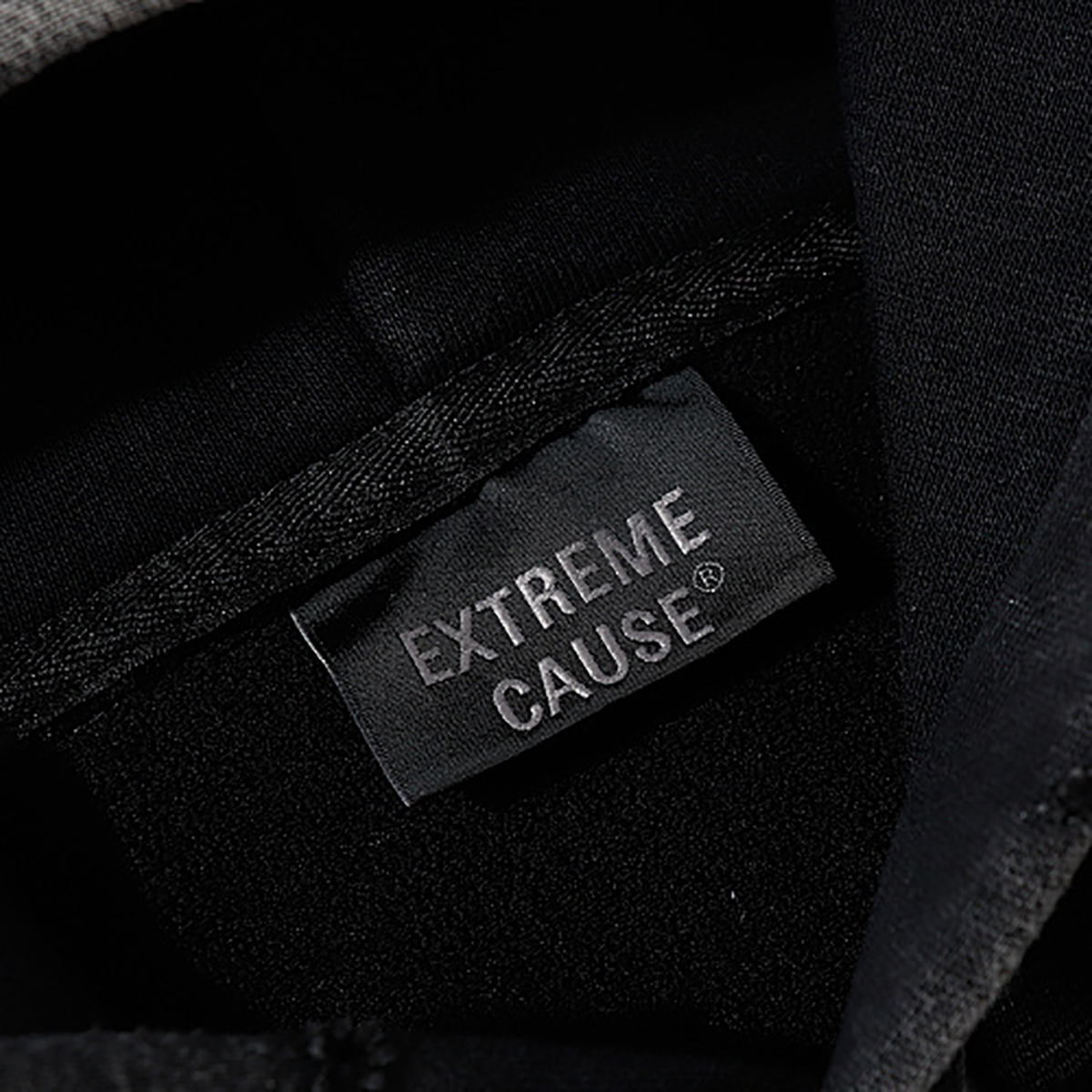 Close-up of men's black heavyweight hoodie brand label, EXTREME CAUSE
