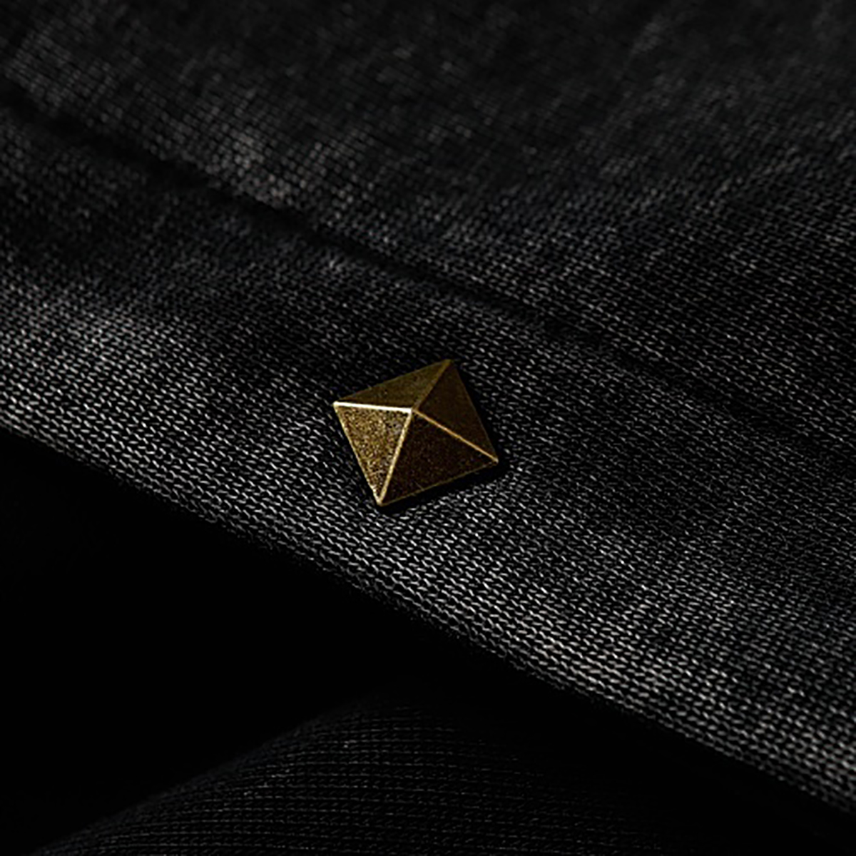 Close-up of pyramid-shaped metal rivet detail on black high street spray-painted distressed zip-up hoodie