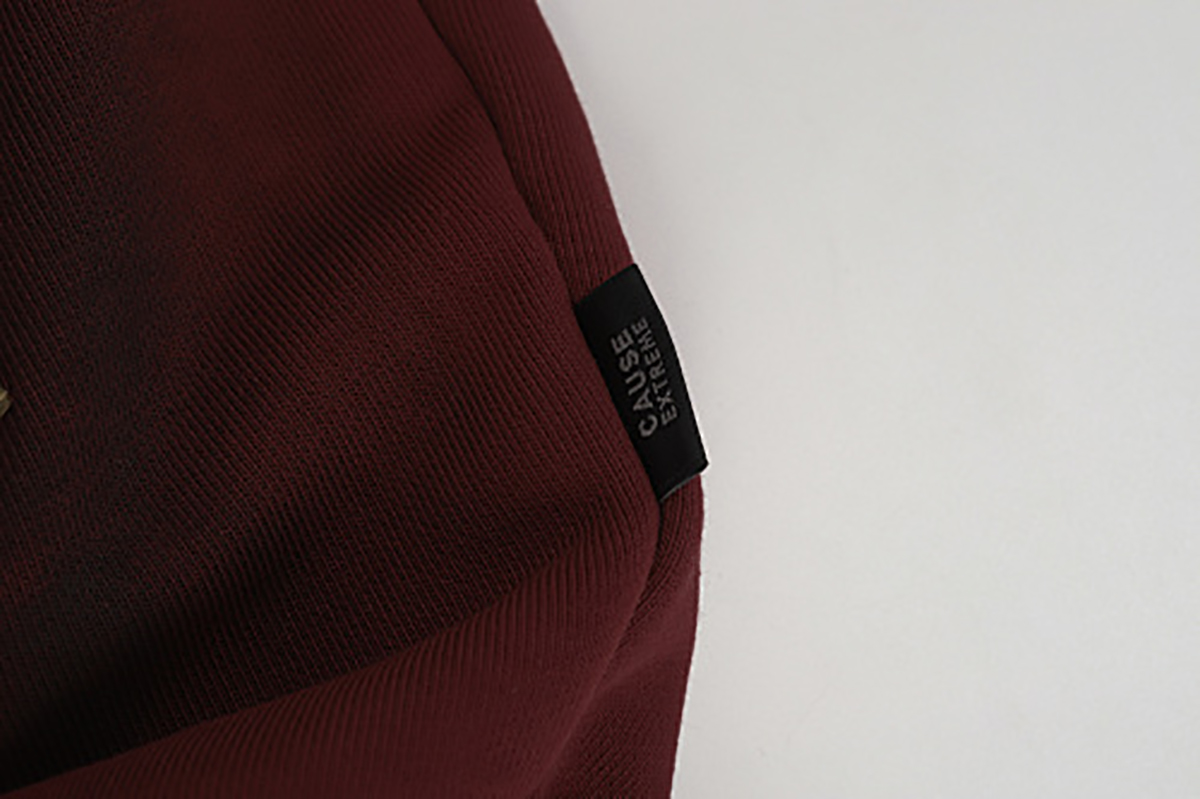 Close-up of burgundy hooded zip-up sweatshirt showing side brand label detail