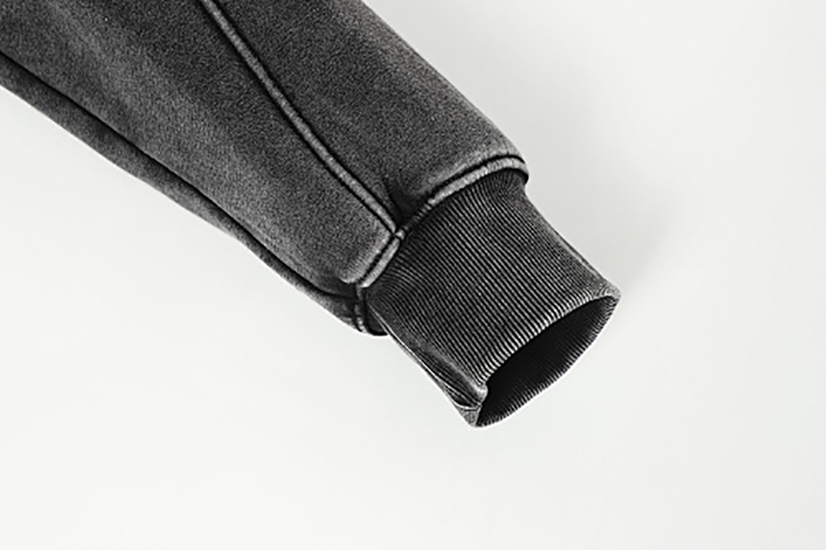 Close-up of men's black American heavyweight vintage deconstructed patchwork fleece-lined hoodie, showing ribbed cuff detail