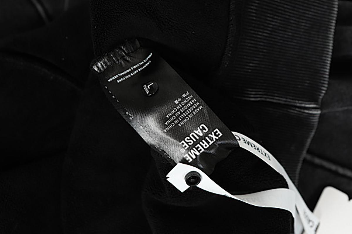 Close-up of men's black American heavyweight vintage deconstructed patchwork fleece-lined hoodie, showing care label detail