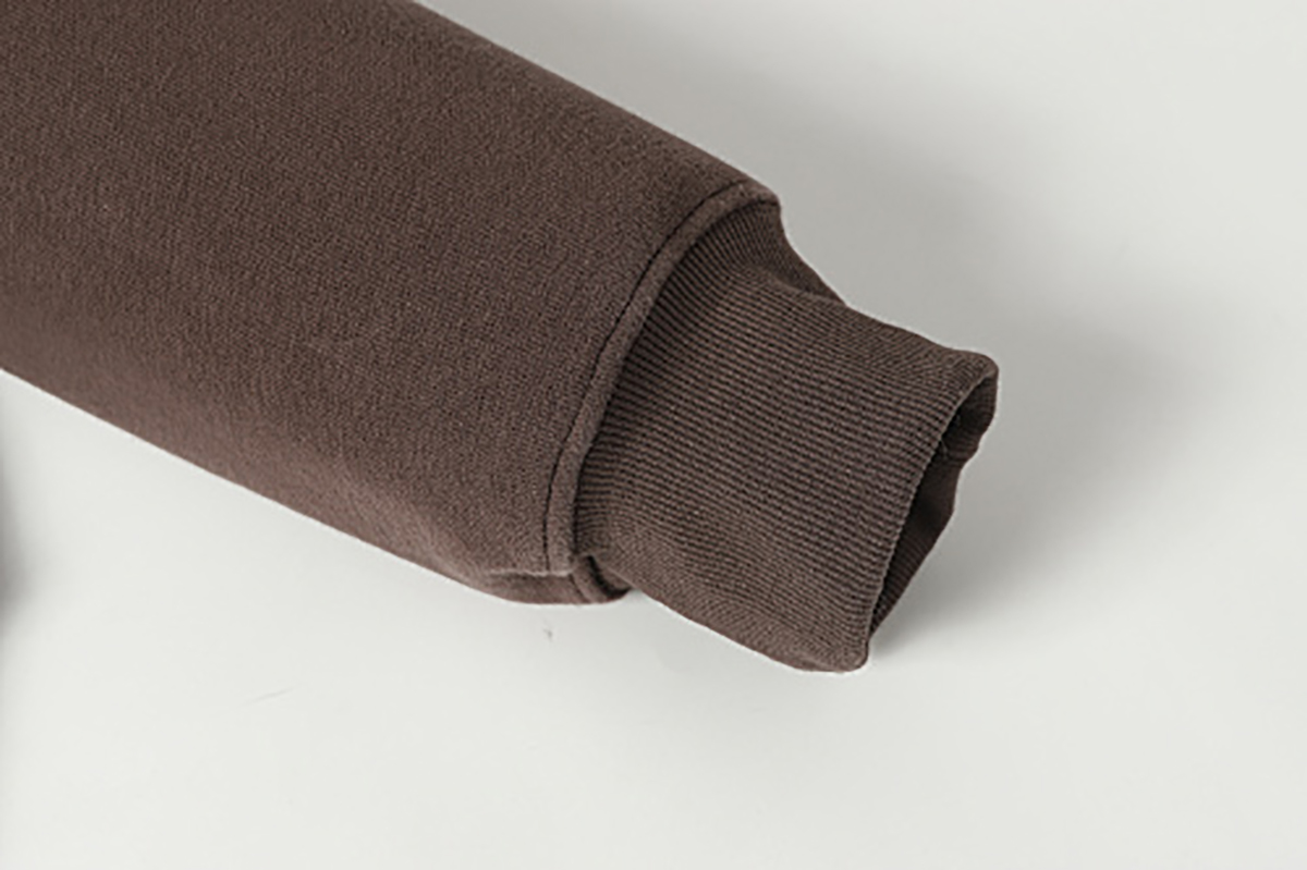 Close-up of men's coffee brown American retro patchwork hooded sweatshirt, showing ribbed sleeve cuff detail
