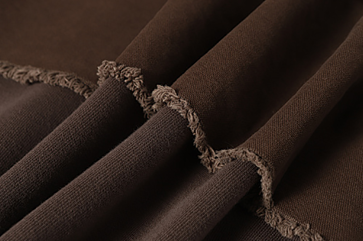 Close-up of men's coffee brown American retro patchwork hooded sweatshirt, showing frayed stitching detail