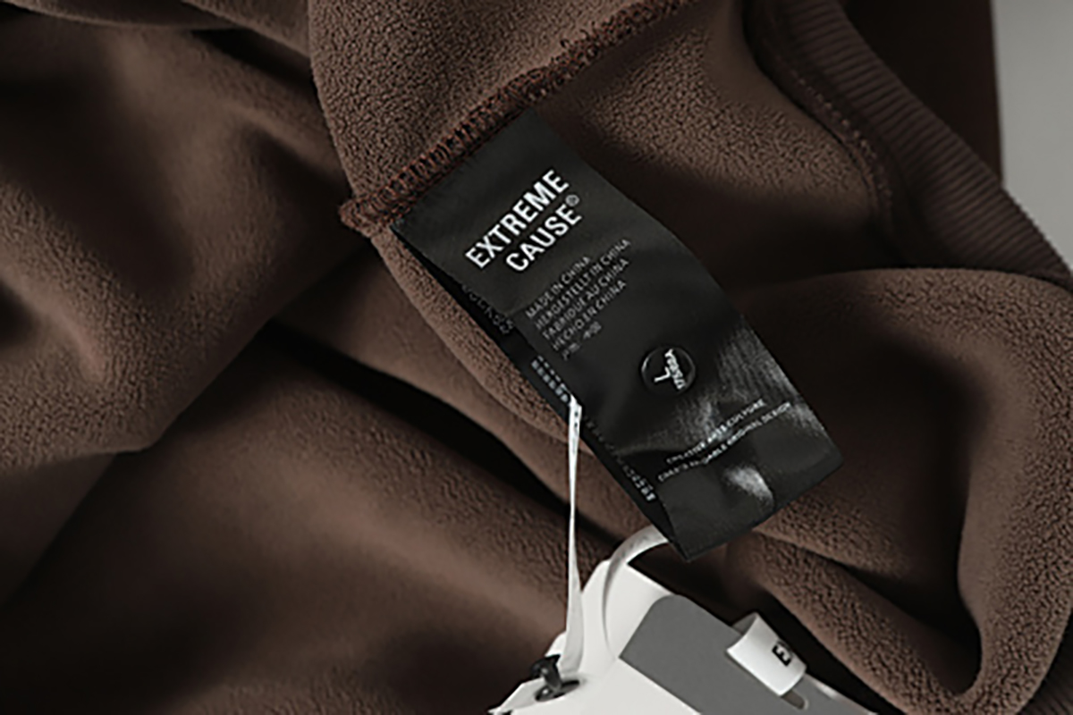 Close-up of men's coffee brown American retro patchwork hooded sweatshirt, showing brand tag and label detail