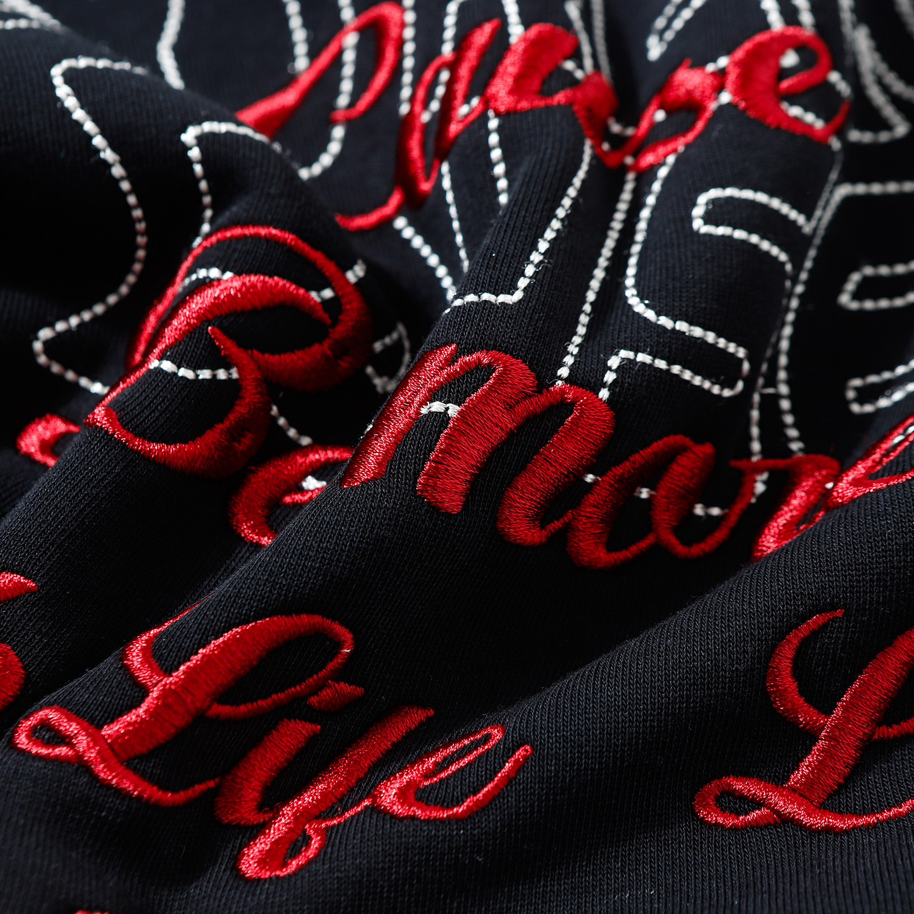 Close-up of red script embroidery on black hoodie fabric
