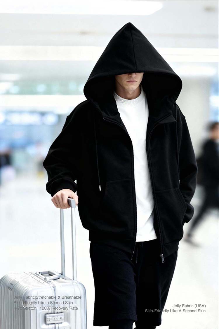 Man wearing black inflatable hoodie, traveling with suitcase, airport lifestyle shot