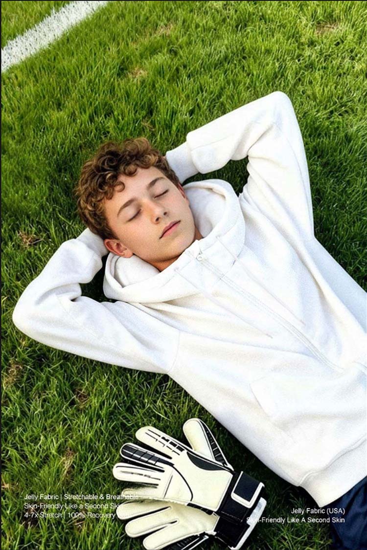 Young man wearing white inflatable hoodie lying on grass, casual outdoor lifestyle shot with soccer gloves