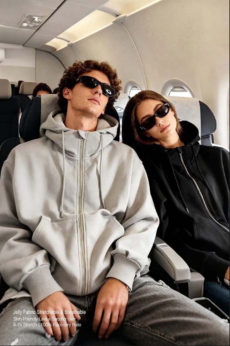 Couple wearing light gray and black inflatable hoodies relaxing on airplane, travel lifestyle shot
