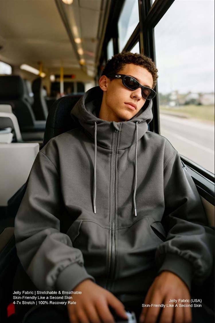 Man wearing dark gray inflatable hoodie relaxing on bus, travel lifestyle shot